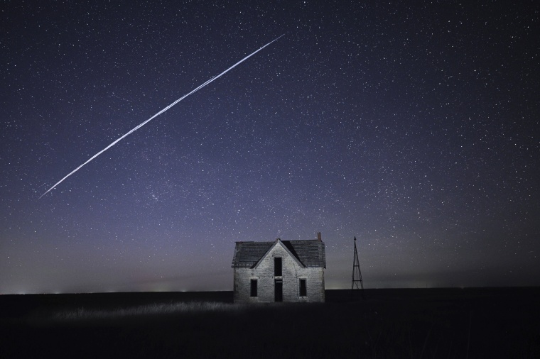 A string of SpaceX StarLink satellites passes over an old stone house near Florence, Kan., on May 6, 2021.