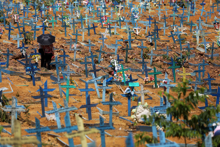 People stand near graves where the people who died of Covid-19 were buried after the city hall opened access to the Parque Taruma cemetery before National Mother's Day in Manaus, Brazil, on May 7, 2021.