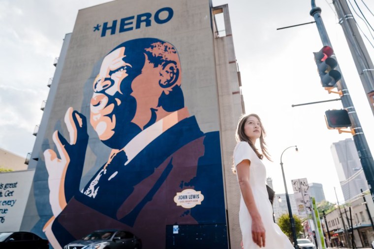Image: Bee Nguyen poses in front of a mural of John Lewis.