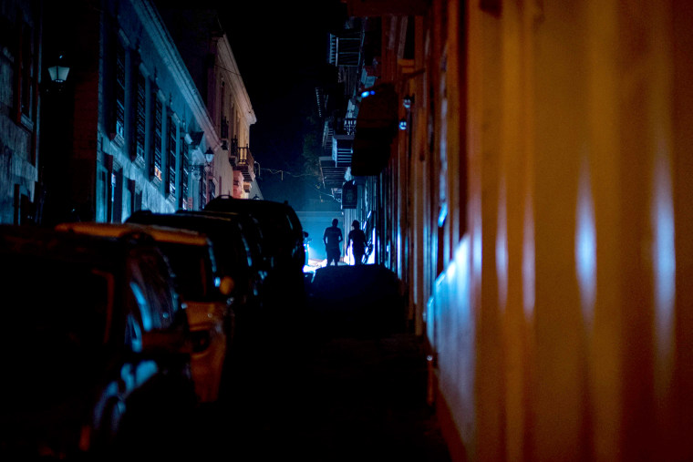 Image: People are seen walking in a street left in darkness by a power outage due to a cyberattack in Old San Juan, Puerto Rico, June 10, 2021.