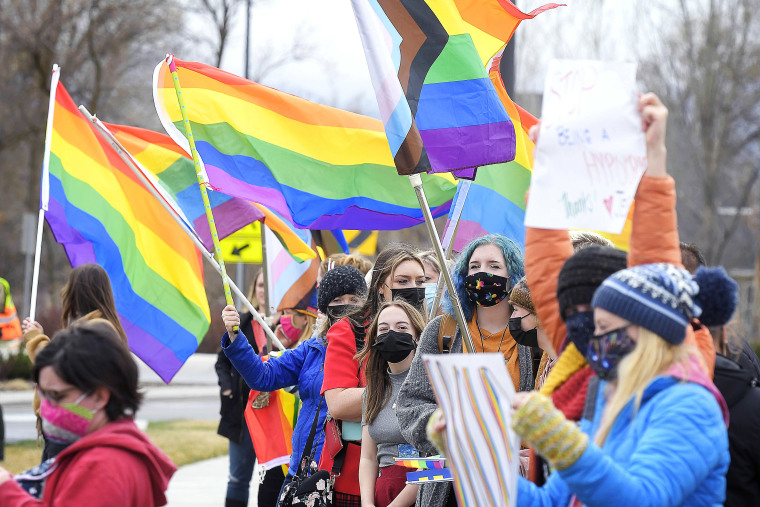 People wave pride flags and hold signs during a rally in support of LGBTQ students on April 14 in Millville, Utah.