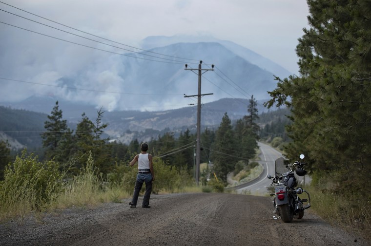 Image: A man watches as a wildfire burns on the side of a mountain in Lytton, B.C., Canada, on July 1, 2021.