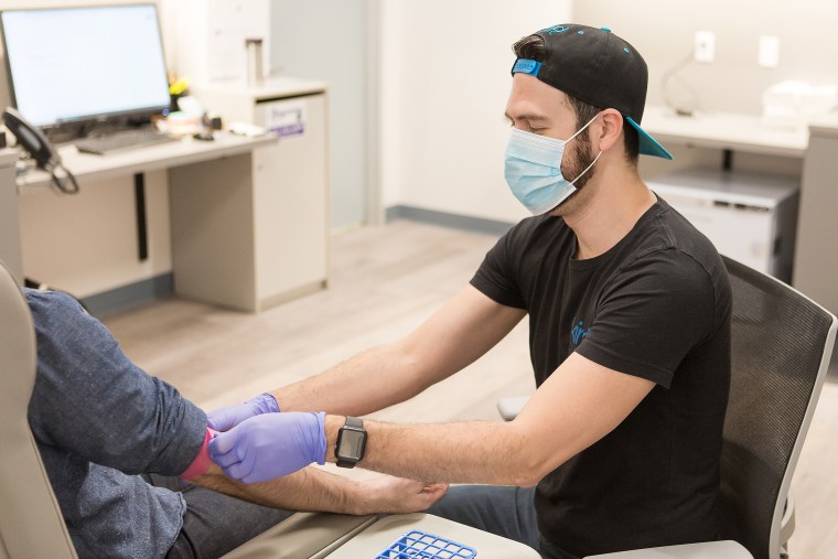 Image: Laboratory Technician Brady Robles draws blood from a patient.