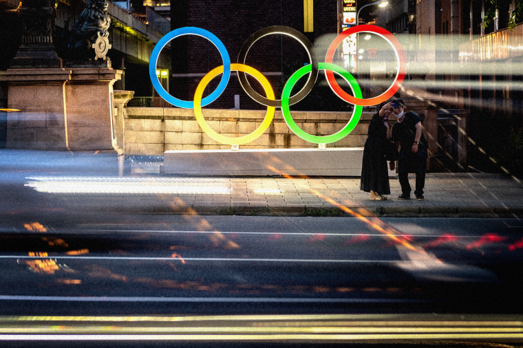 Image: A couple pose in front of the Olympic Rings in Tokyo's Nihonbashi district on July 10, 2021.