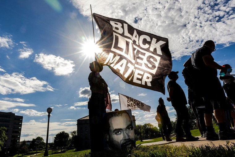 A woman holds a Black Lives Matter flag during an event in remembrance of George Floyd outside the Minnesota State Capitol on May 24, 2021 in Saint Paul, Minn.