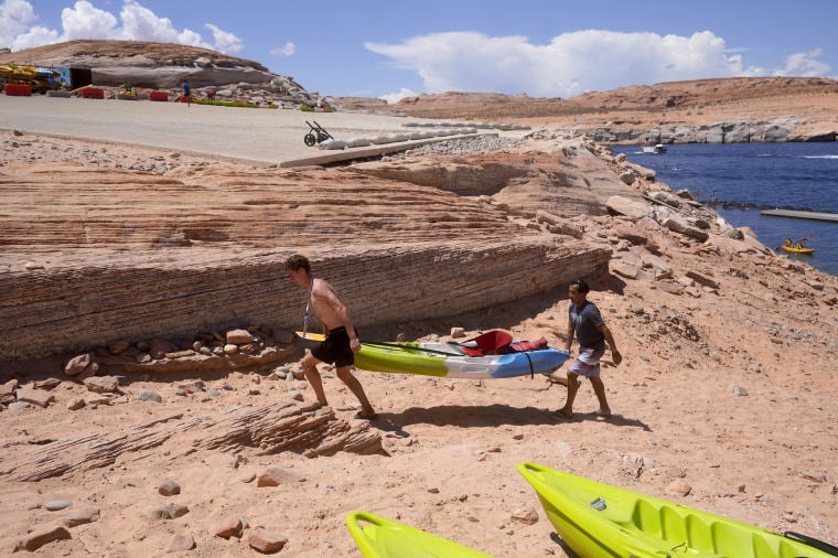 Visitors carry a kayak up a newly exposed cliff face beneath the closed Antelope Point launch ramp on Lake Powell, near Page, Ariz.