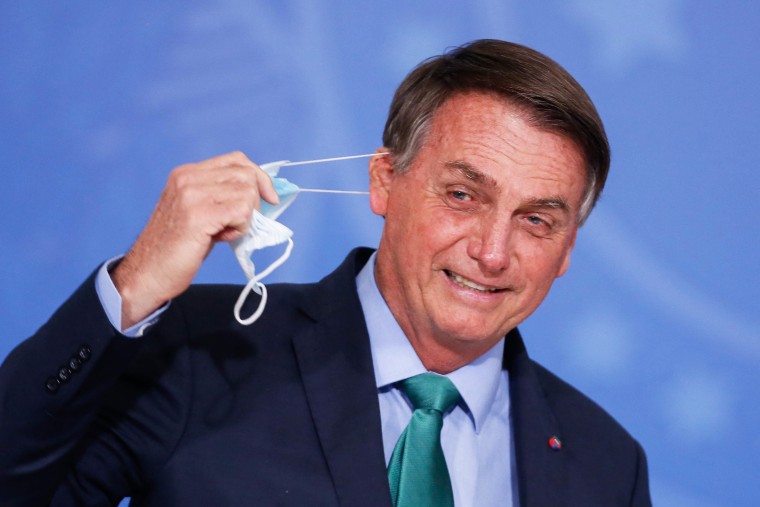 Brazil's President Jair Bolsonaro removes his facemask during a ceremony at the Planalto Palace in Brasilia on Aug. 5, 2021.