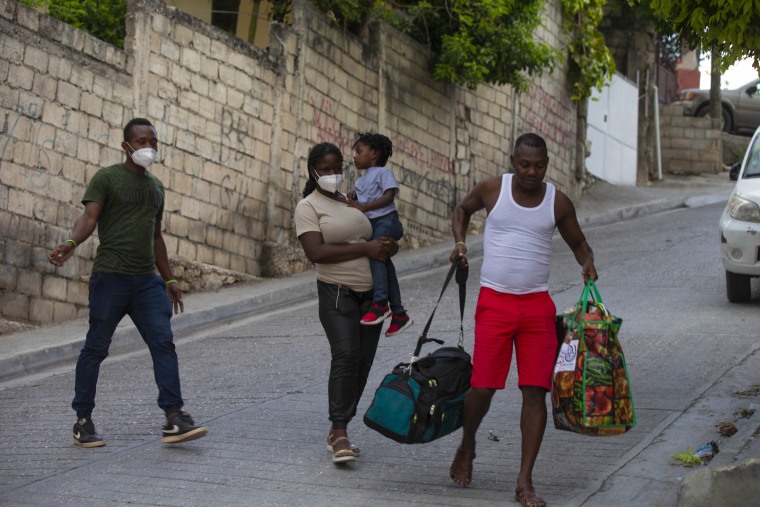Jean Charles Celestin (derecha) carga el equipaje de su primo Jhon Celestin (izquierda), su esposa Delta De Leon, y su hija  Chloe, en Puerto Príncipe, Haití, el miércoles 22 de septiembre de 2021.