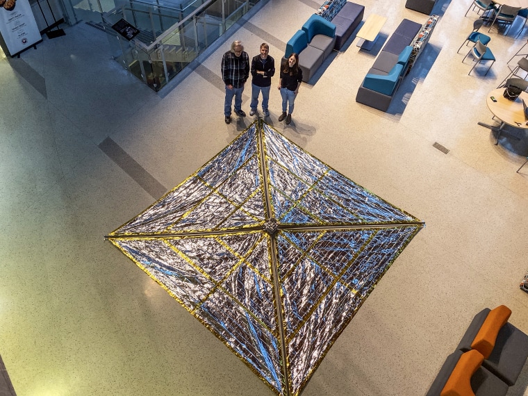 Anthony Cofer, David Spencer, and Arly Black stand with Spinnaker3, a drag sail prototype, fully deploying in the atrium of the Neil Armstrong Hall of Engineering at Purdue University, January 2020.