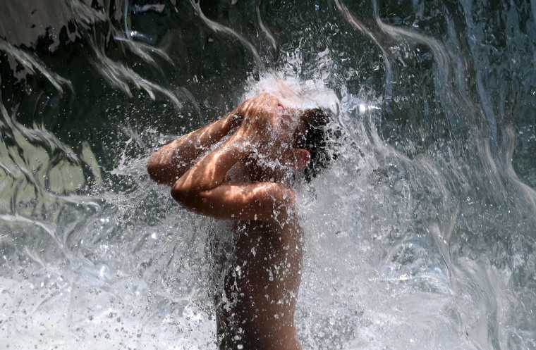 Image: A young boy cools down in a waterfall at Yards Park in Washington on Aug. 12, 2021, as a heat wave hit the region.