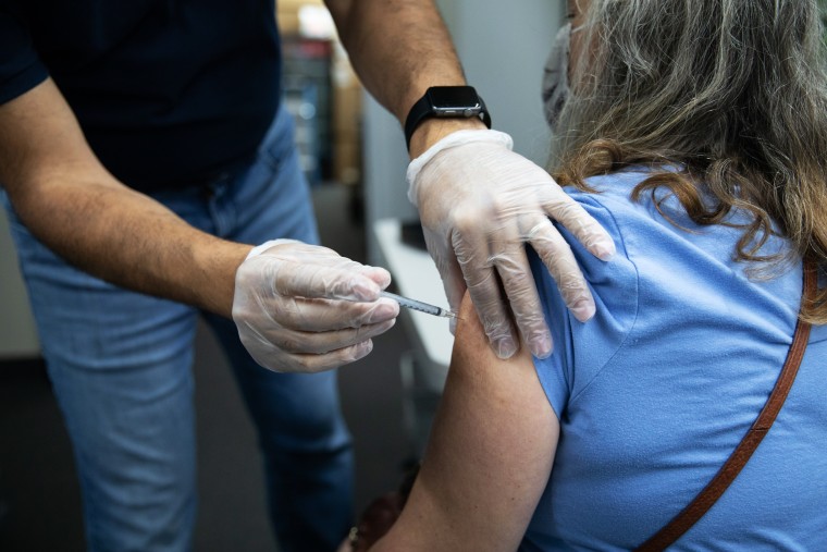 A pharmacist administers a third dose of the Pfizer-BioNTech Covid-19 vaccine to a customer at a pharmacy in Livonia, Mich., on Aug. 17, 2021.