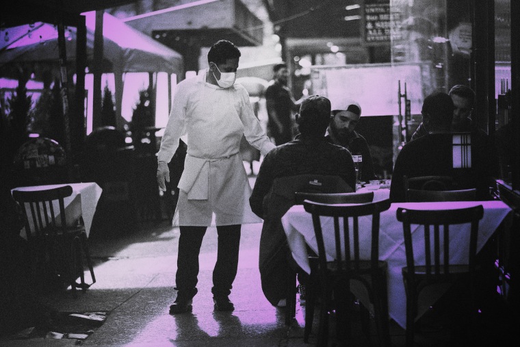 IMage: A restaurant employee moves between tables in Manhattan on Dec. 11, 2020.