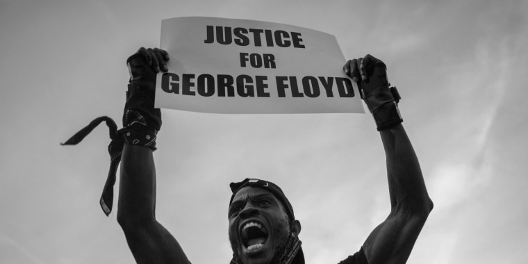 Image: A Black Lives Matter protester holds a placard  that reads,"Justice for George Floyd".
