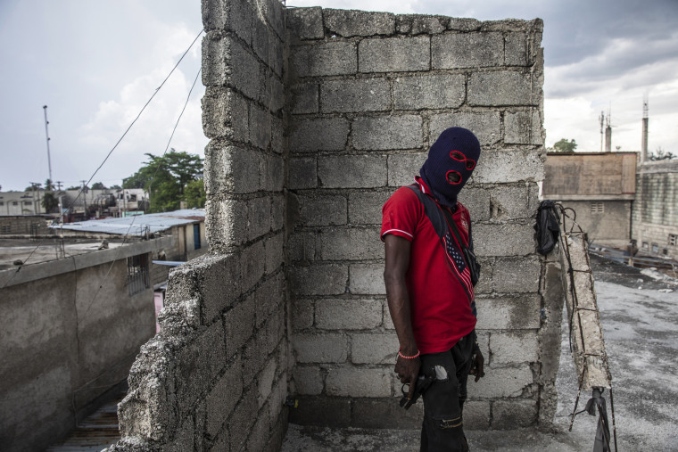 A gang member, wearing a balaclava and holding a gun, poses for a photo in the Portail Leogane neighborhood of Port-au-Prince, Haiti, on Sept. 16, 2021.