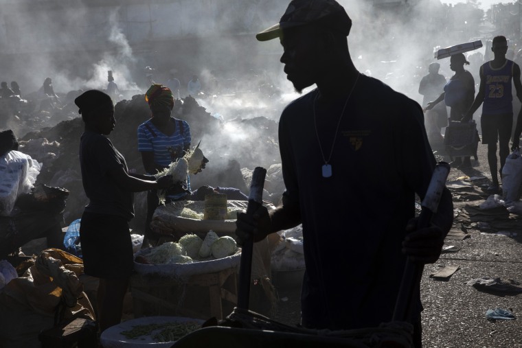 Vendors shred cabbage in the Croix des Bosalles market in Port-au-Prince, Haiti, on Sept. 13, 2021. To enter the market, one must walk through a gang gauntlet.