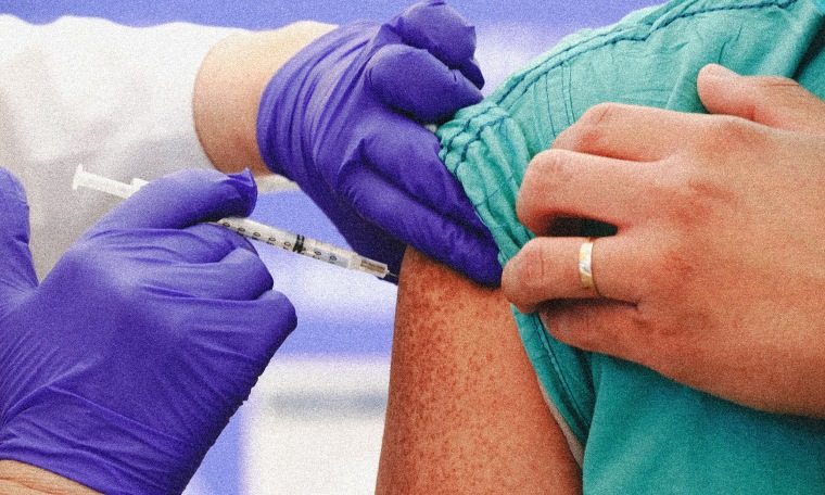 Image: Hands of a medical professional wearing surgical gloves holding a syringe.