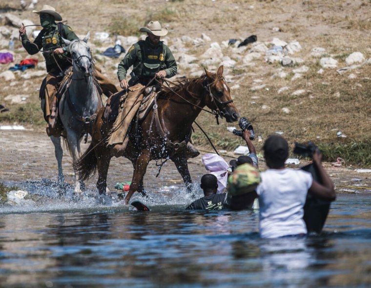 Agentes de la Patrulla Fronteriza a caballo intentan contener el cruce de migrantes haitianos por el Río Grande.