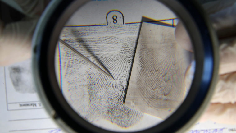 Una huella dactilar en una hoja de papel bajo una lupa para estudio en un laboratorio.