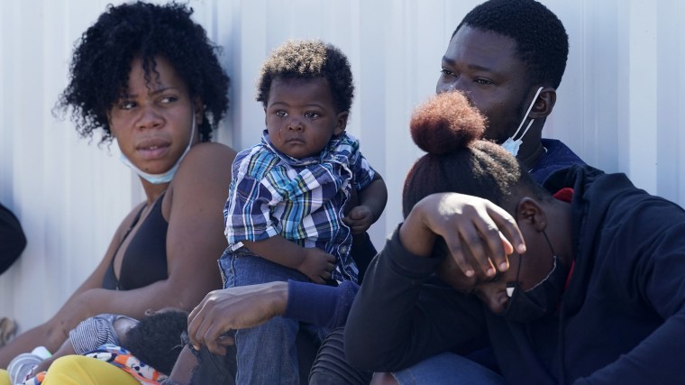 Familias migrantes, muchas de ellas procedentes de Haití, esperan un autobús después de haber sido procesadas y liberados tras pasar un tiempo en un campamento improvisado cerca del Puente Internacional Del Río en Texas, el lunes 20 de septiembre de 2021.