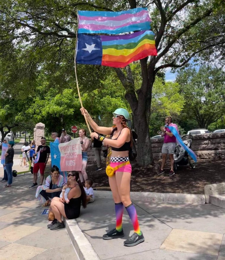 The Rev. Remington Johnson waves pride flags at a rally in Austin in May.