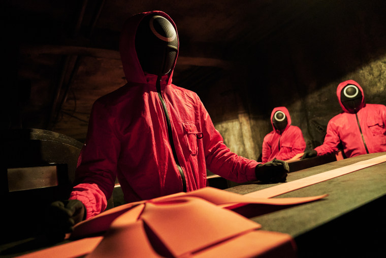 Masked staff handle boxes holding the dead bodies of contestants in the Korean survival drama "Squid Game" on Netflix.