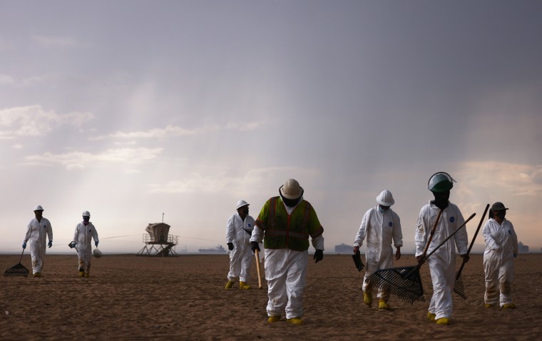 Image: Cleanup workers in protective suits depart the closed Huntington State Beach as a storm approaches after a 126,000-gallon oil spill from an offshore oil platform on Oct. 4, 2021 in Huntington Beach, Calif.