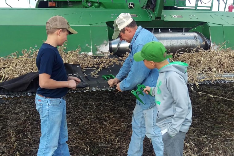 Image: David Misener works on a combine harvester with his sons.