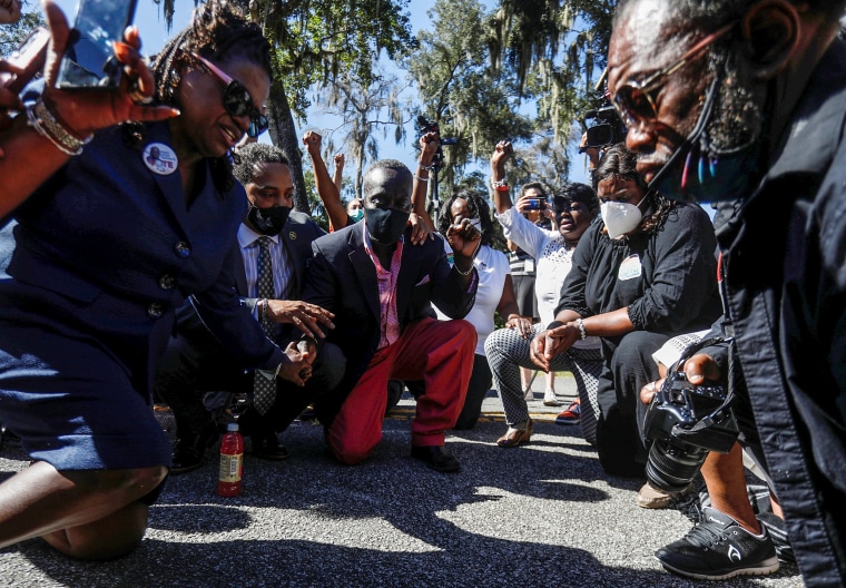 People pray as they visit Satilla Shores neighborhood, where Ahmaud Arbery was killed, in Brunswick, Ga., on Oct. 19, 2021.