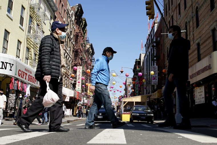 Image: People cross a street in New York's Chinatown on March 21, 2021.