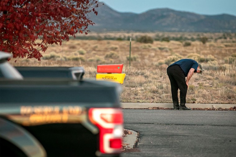 Alec Baldwin crouches down in the parking lot outside the Santa Fe County Sheriff's offices after being questioned on the shooting.