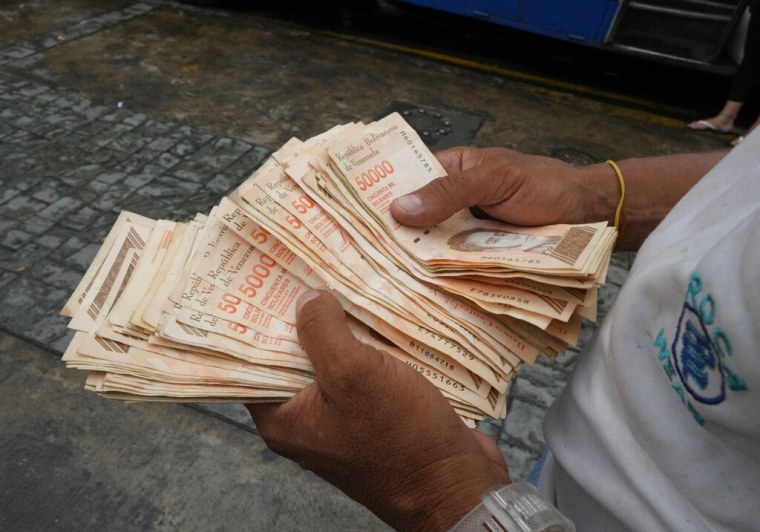 Un hombre cuenta billetes por el equivalente a un dólar en una parada de autobús en Caracas el 5 de agosto de 2021.
