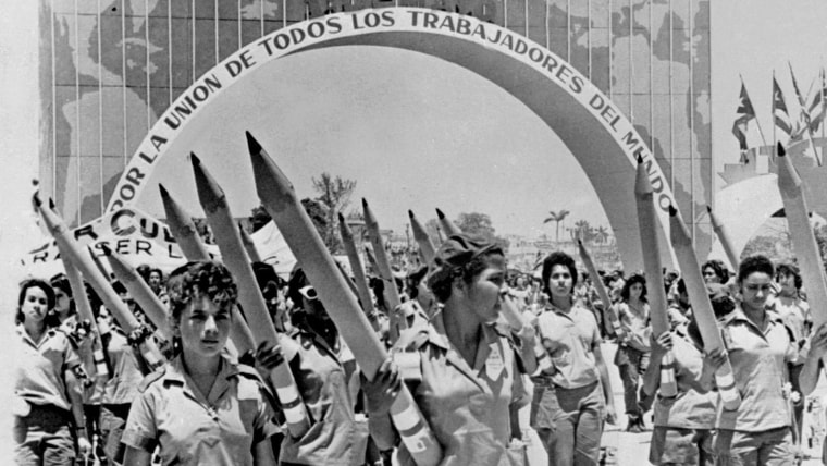 Integrates de una brigada de alfabetización cubana caminan en La Habana en 1961 con lápices gigantes en representación de su labor.
