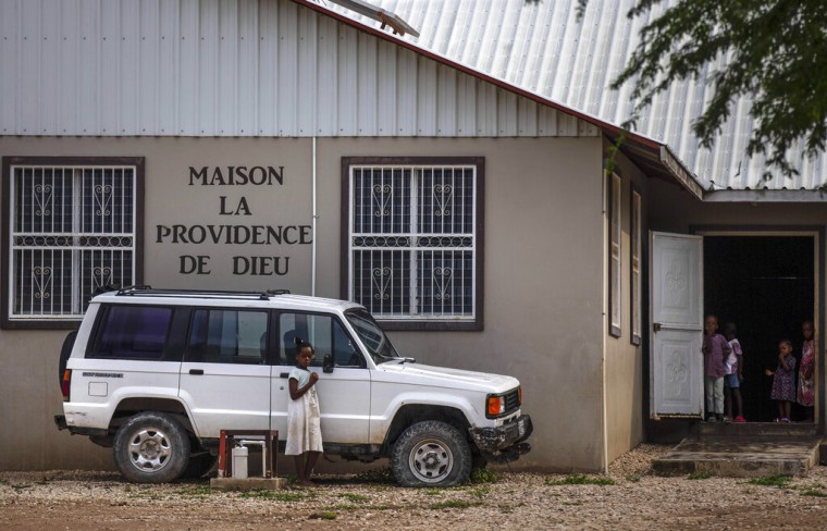 Varios niños de pie frente a la entrada de la sede de la misión cristiana 'Maison La Providence de Dieu', a la que pertenecen las 17 personas que fueron secuestradas por una pandilla en Puerto Príncipe, Haití
