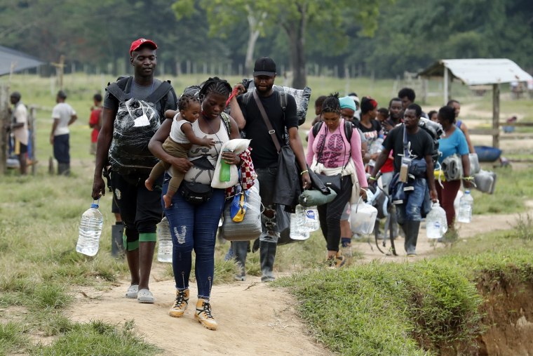 Migrantes haitianos cargan sus pertenencias para instalarse en un campamento donde pasarán la noche para iniciar su viaje hacia el Tapón del Darién, el 27 de septiembre de 2021, en Acandi, Colombia.