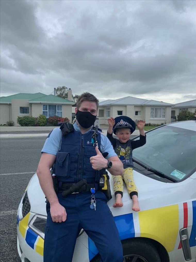 El agente Constable Kurt se sienta sobre su coche patrulla con un niño de 4 años, en la ciudad de Invercargill, Nueva Zelanda, el 15 de octubre de 2021.