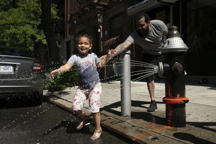Ally Rogers, de 5 años, juega en agua de una boca de incendios con su padre Allen, el martes 28 de julio de 2020 en Nueva York.