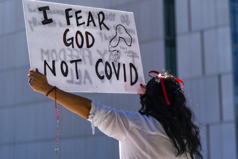Una mujer que se opone a los mandatos de vacunación del COVID-19 sostiene un cartel frente al Ayuntamiento en el centro de Los Ángeles. 18 de septiembre de 2021.
