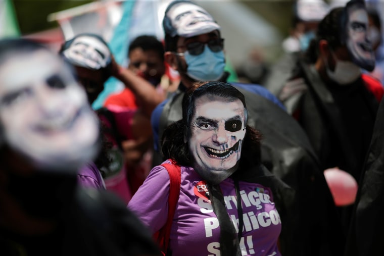 Manifestantes con máscaras que representan al presidente brasileño Jair Bolsonaro participan en una protesta contra su Gobierno, en el Palacio de Planalto en Brasilia, Brasil 20 de octubre de 2021.