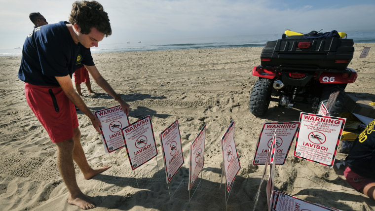 El domingo los socorristas pusieron carteles en Huntington Beach para advertir que el contacto con el agua puede causar enfermedades.