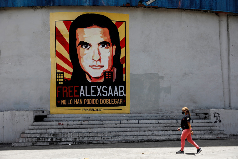 Image: A woman walks by a mural in support of the liberation of Colombian businessman and envoy Alex Saab, who is detained in Cape Verde on charges of laundering money for the government of Venezuelan President Nicolas Maduro, in Caracas, Venezuela on Sept. 9, 2021.