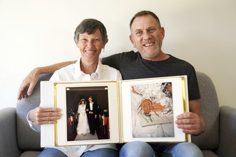Cyndi and Brad Marler sit for a portrait with their 1989 wedding album at Cyndi's apartment on Oct. 18, 2021, in Chicago. A lot can be hidden behind a marriage. For the Marlers, it was that they are both gay. A few years after their wedding, they told each other their secret. Then, for more than three decades, they told no one else.
