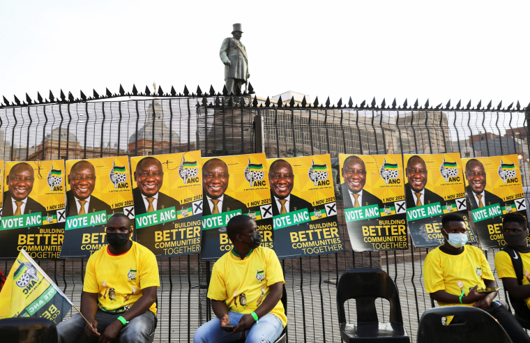 Supporters of the African National Congress wait beneath posters of South African President Cyril Ramaphosa in Pretoria, South Africa, on Sept. 27, 2021.