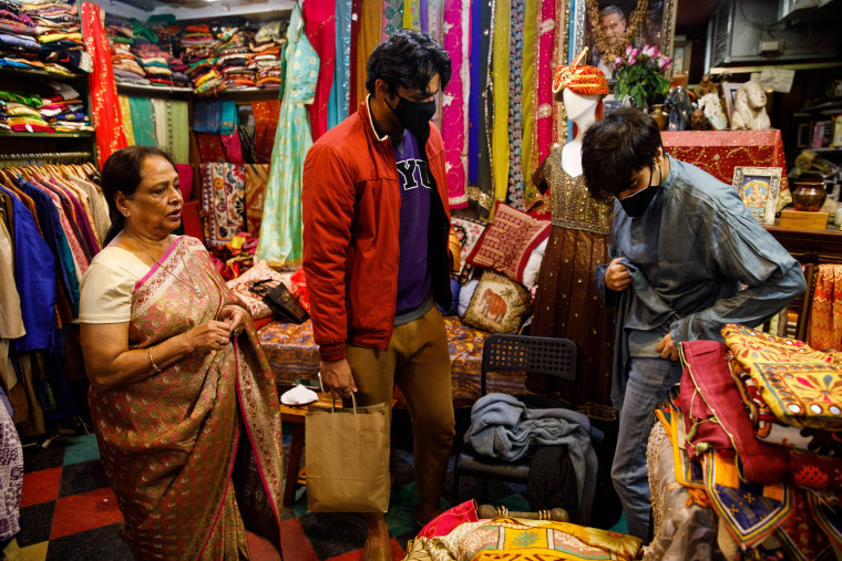 Saroj Goyal helps Yaman Walia, center, and Vidur Bahl, right, with selecting the right size of kurta at her clothing boutique, Dress Shoppe II, on the Lower East Side in New York on Nov. 4, 2021.