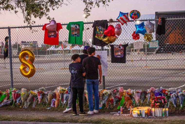Local high school students who attended the Travis Scott concert, Isaac Hernandez and Matthias Coronel, watch Jesus Martinez sign a remembrance board at a makeshift memorial on Nov. 7, 2021 at NRG Park in Houston.