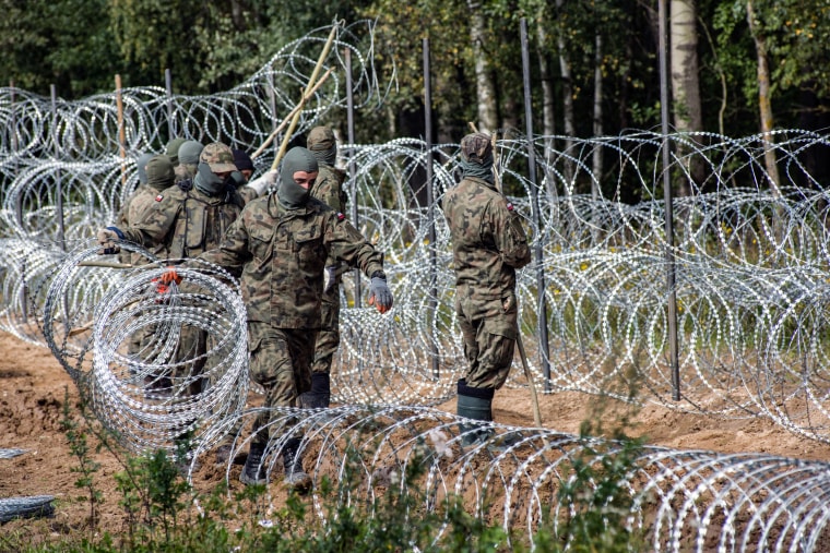 Polish soldiers are seen building a razor wire fence along