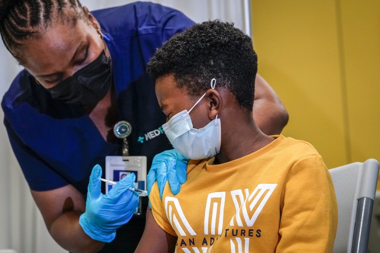 Image: Tse Cowan, 8, watches as Registered Nurse Sobrina Laurent, left, inoculates him with first dose of the Pfizer-BioNTech Covid-19 vaccine on Nov. 8, 2021, at P.S. 19 in the East Village neighborhood of New York.