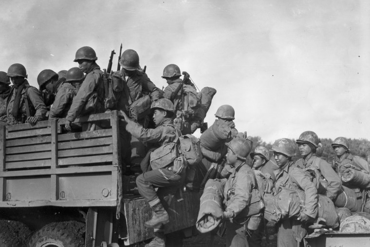 Japanese American troops in the segregated 442nd Regimental Combat Team climb into a truck at a military campsite in France during World War II. 