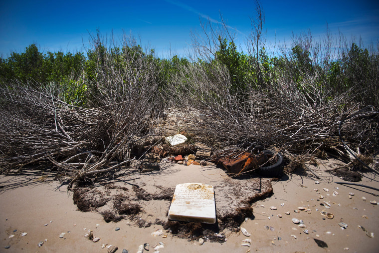Image: A grave stone rests on the beach where a cemetery once stood but has been washed away due to erosion in an area called Canaan in Tangier, Va., on May 16, 2017.