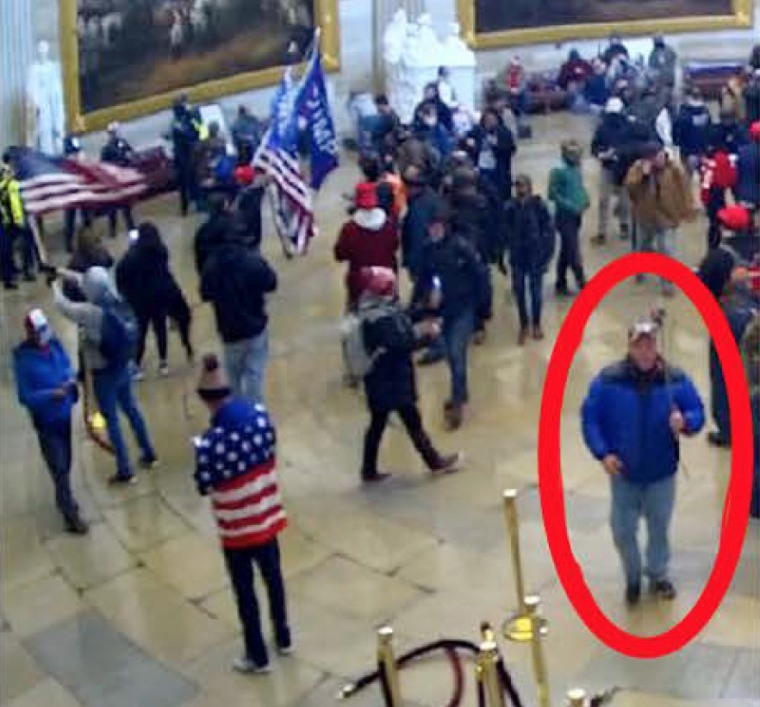 Boyd Allen Camper, circled in red, walks through the Capitol Rotunda on Jan. 6, 2021, holding what appears to be a camera on a pole.