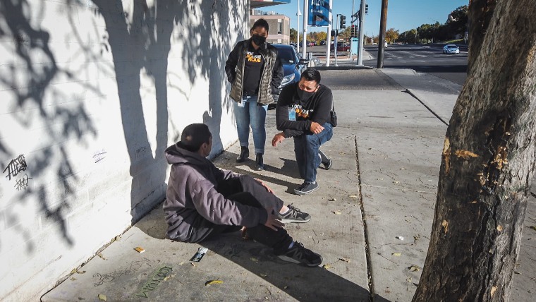 Two public safety behavioral health responders speak to a man on the street in Albuquerque, N.M.